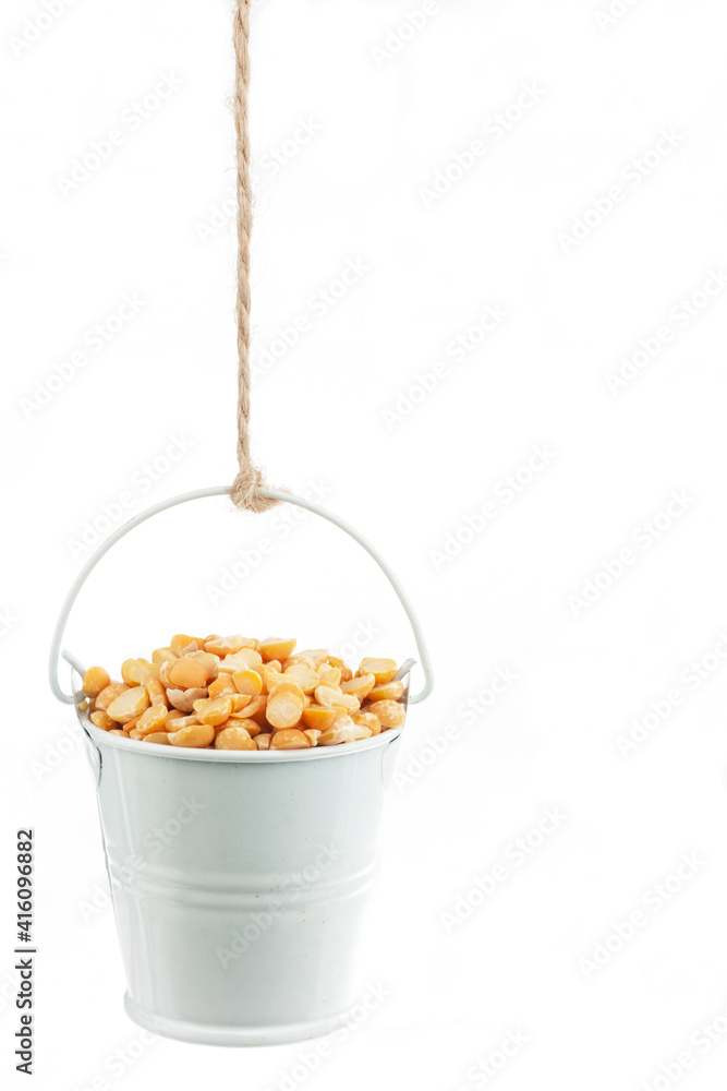 A full bucket of peas grains hanging from a rope. A full bucket of peas grains hanging from a rope.