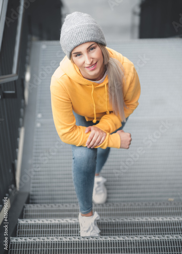 Above view of smiling full length beautiful young woman standing. Outdoors daylight. Pretty smile girl wearing casual clothing.