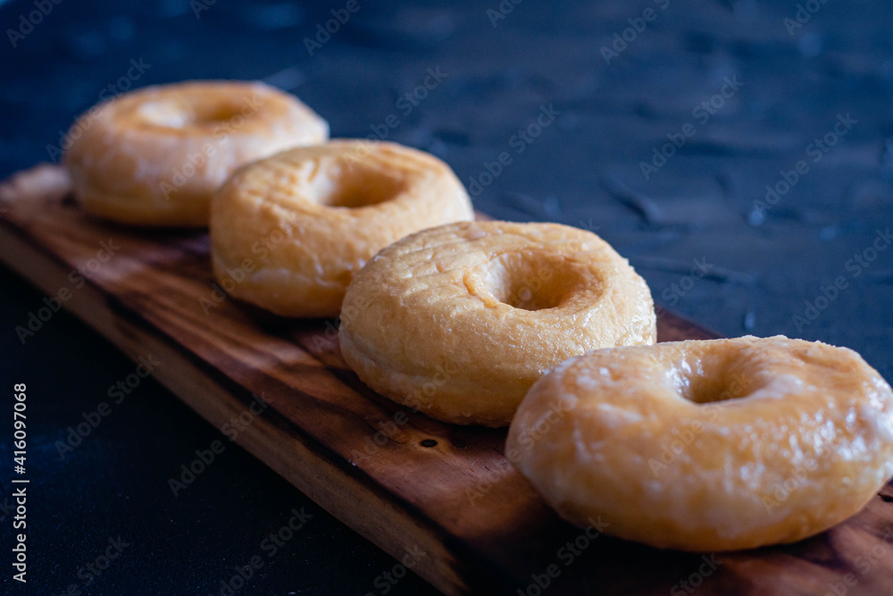 glazed donuts on wooden base with dark background glazed donuts on wooden base with dark background
