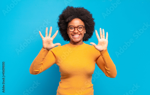 фотографія smiling and looking friendly, showing number ten or tenth with hand forward, co