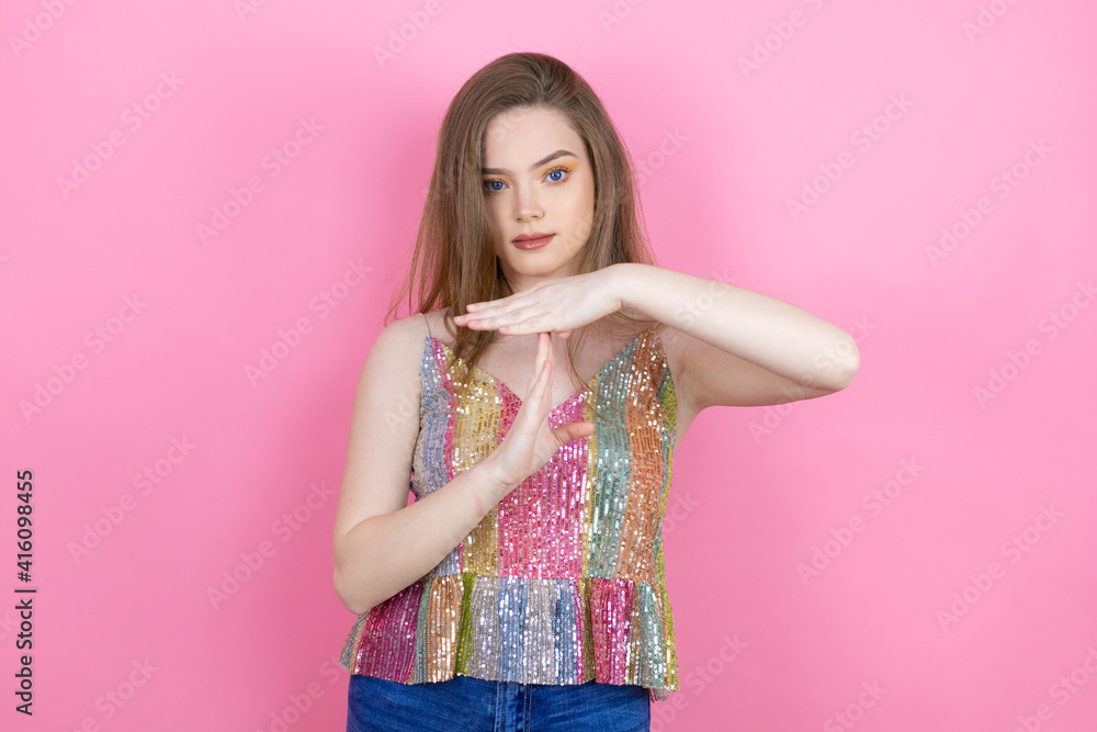 Pretty redhead woman wearing a shiny top standing over pink background Doing time out gesture with hands, frustrated and serious face Pretty redhead woman wearing a shiny top standing over pink background Doing time out gesture with hands, frustrated and serious face