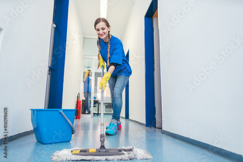 Fotografie Cleaning lady mopping the floor in an office building