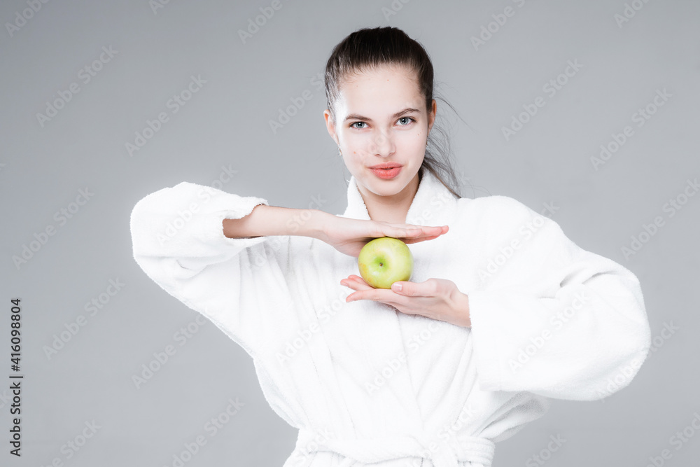 Woman in white coat smiling holding an apple in one hand and leaning against her face with the other Woman in white coat smiling holding an apple in one hand and leaning against her face with the other