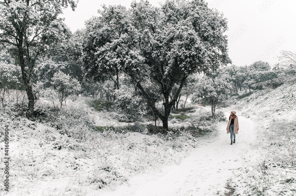 Obraz premium Woman in outerwear walking in snowy woods