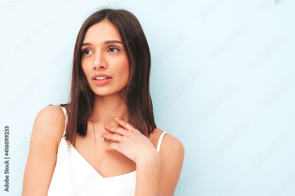 Portrait of beautiful smiling woman dressed in white pajamas. Sexy carefree cheerful model enjoying her morning. Adorable and positive female posing near light blue wall in studio. Tanned and skinny Portrait of beautiful smiling woman dressed in white pajamas. Sexy carefree cheerful model enjoying her morning. Adorable and positive female posing near light blue wall in studio. Tanned and skinny