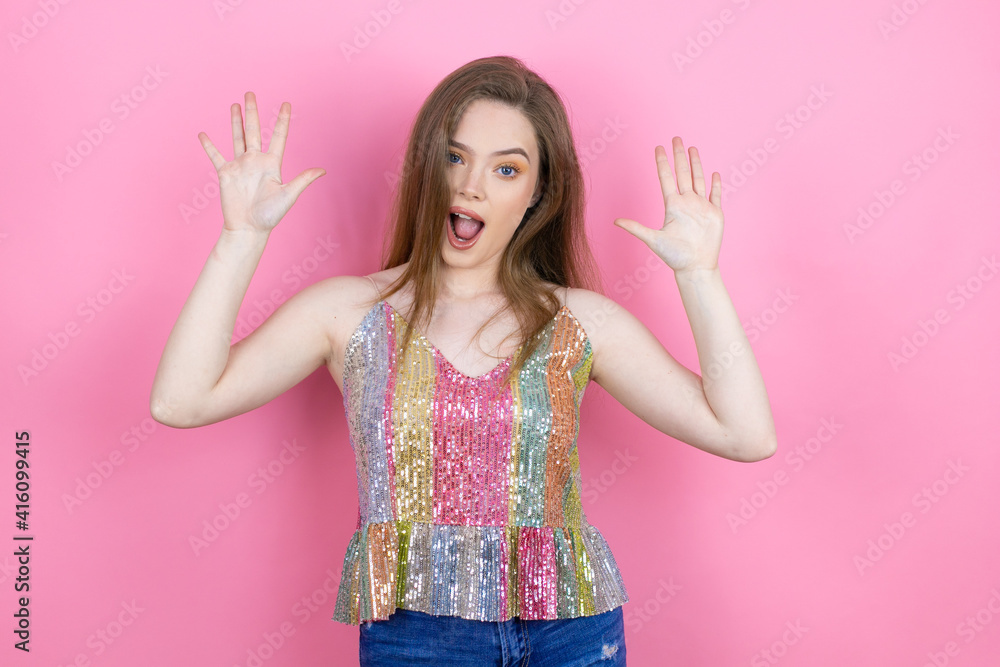 Pretty redhead woman wearing a shiny top standing over pink background showing and pointing up with fingers number ten while smiling confident and happy Pretty redhead woman wearing a shiny top standing over pink background showing and pointing up with fingers number ten while smiling confident and happy