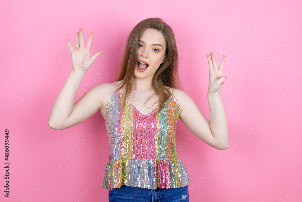 Pretty redhead woman wearing a shiny top standing over pink background showing and pointing up with fingers number eight while smiling confident and happy Pretty redhead woman wearing a shiny top standing over pink background showing and pointing up with fingers number eight while smiling confident and happy