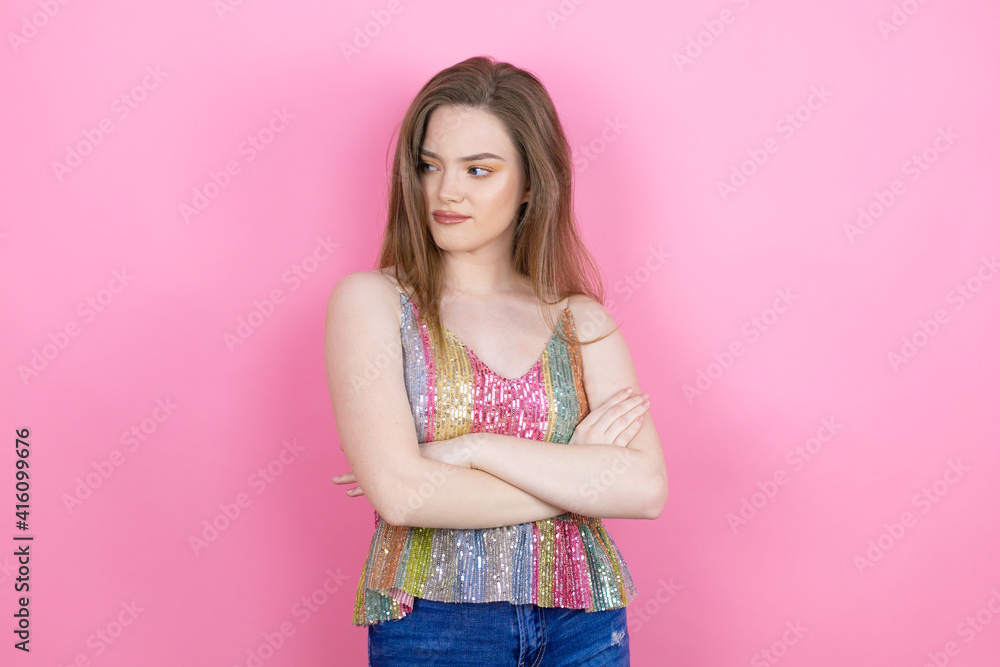 Pretty redhead woman wearing a shiny top standing over pink background thinking looking tired and bored with crossed arms Pretty redhead woman wearing a shiny top standing over pink background thinking looking tired and bored with crossed arms