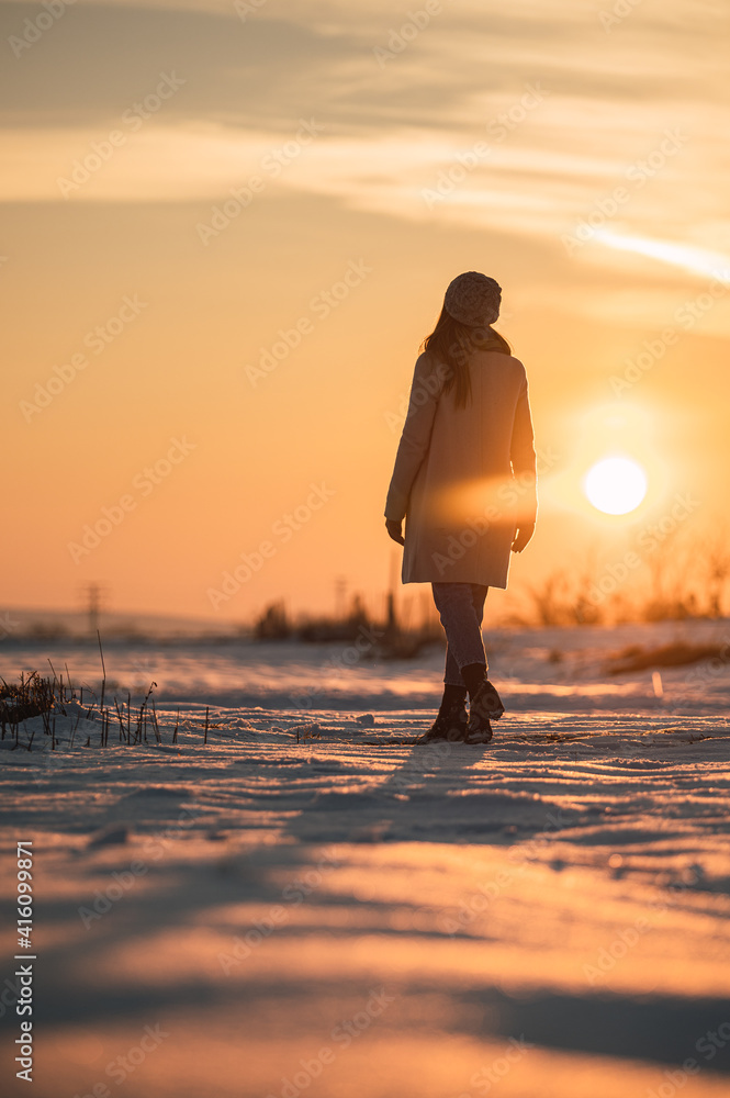 Fototapeta premium Woman enjoying sunset in snowy field