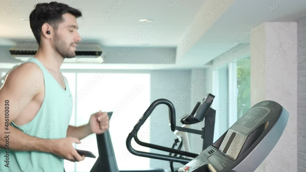 Middle eastern male exercise on treadmill running and listen to music with Smartphone. fitness gym healthy lifestyle. Slow motion Middle eastern male exercise on treadmill running and listen to music with Smartphone. fitness gym healthy lifestyle. Slow motion