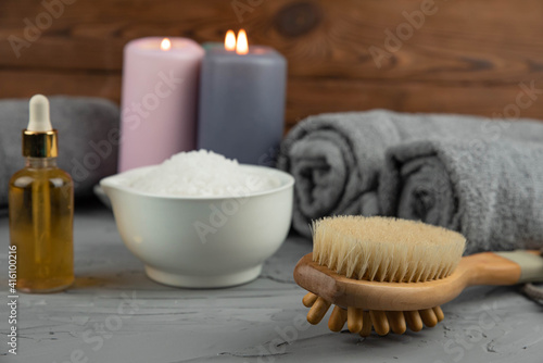 Herbal therapy, traditional medicine and homeopathy concept. Towel with salt, herbs, massage brush, candles and bottle natural organic oil essence serum. Set for spa, massage and aromatherapy 