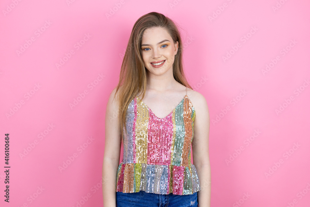 Pretty redhead woman wearing a shiny top standing over pink background with a happy face standing and smiling with a confident smile showing teeth Pretty redhead woman wearing a shiny top standing over pink background with a happy face standing and smiling with a confident smile showing teeth