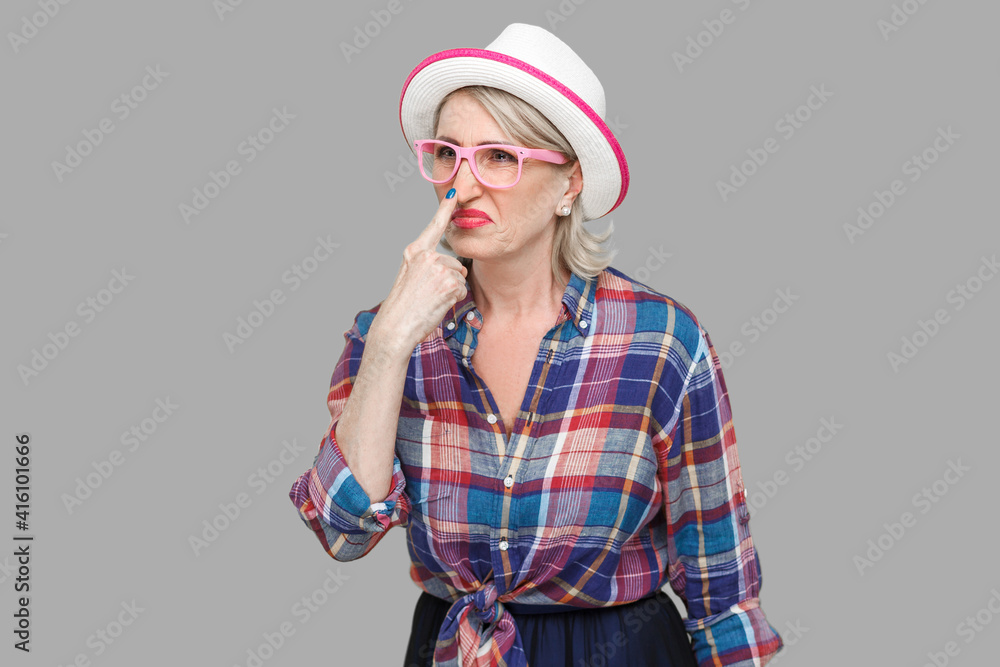 You are liar. Portrait of angry modern stylish mature woman in casual style with hat, eyeglasses standing looking and touching nose with lie gesture. indoor studio shot isolated on gray background. You are liar. Portrait of angry modern stylish mature woman in casual style with hat, eyeglasses standing looking and touching nose with lie gesture. indoor studio shot isolated on gray background.