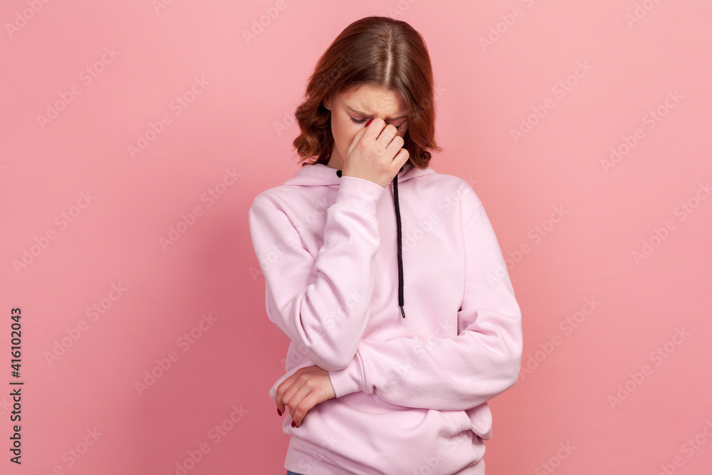 Portrait of upset young woman touching nose and frowning, wiping tears crying, feeling desperate hopeless, coping lonely in emotional stress. Indoor studio shot, isolated on pink background Portrait of upset young woman touching nose and frowning, wiping tears crying, feeling desperate hopeless, coping lonely in emotional stress. Indoor studio shot, isolated on pink background