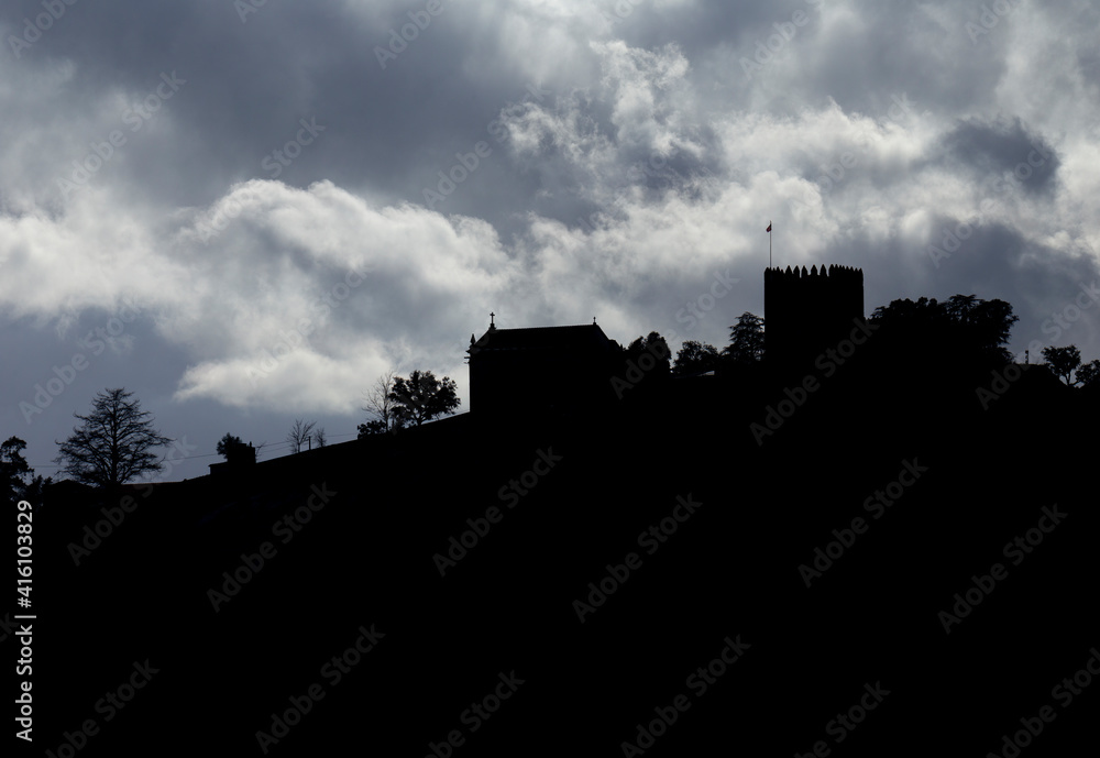 Lanhoso Castle silhouette against the sunlight with a blue and cloudy sky in Povoa de Lanhoso, Portugal.