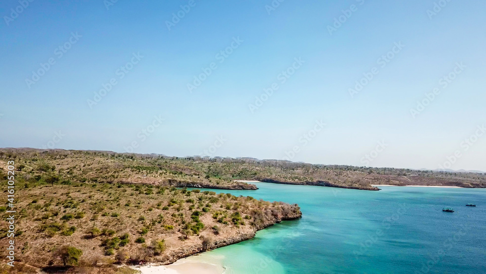 An areal view on idyllic Pink Beach on Lombok, Indonesia. Sea is calm, shining with many shades of blue. Beauty in the nature. Unspoiled hidden gem. Perfect place for peaceful, relaxed holidays