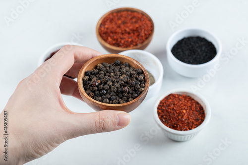 Hand holding a clay bowl full of dried pepper