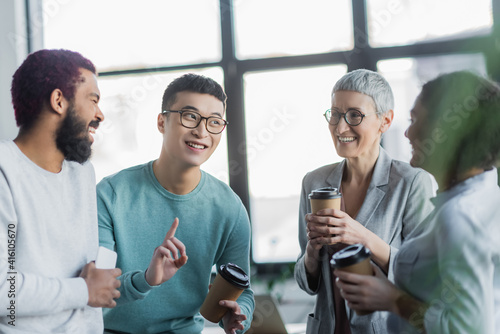 Multiethnic business people with coffee to go and smartphone talking in office