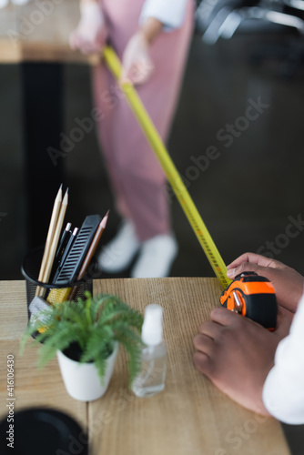 Cropped view of african american businessman using tape measure with colleague