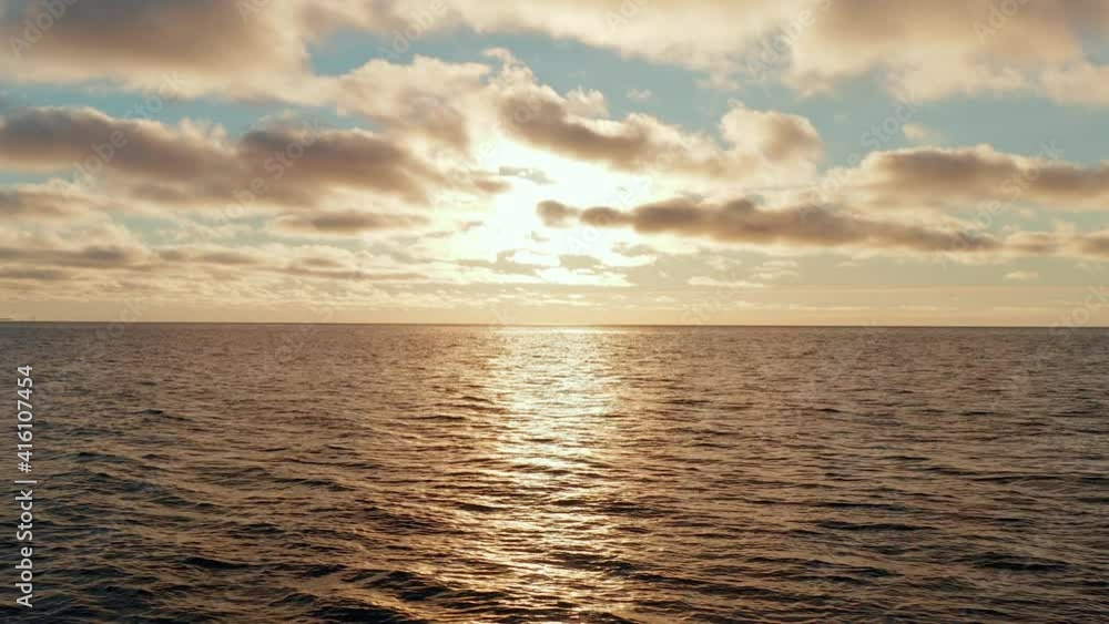 Epic aerial view of golden sunset, sunrise at sea with strong reflection. Calm water with small ripple, large gold pink clouds, bright orange sun light. Slight pan to right. 4k footage. Epic aerial view of golden sunset, sunrise at sea with strong reflection. Calm water with small ripple, large gold pink clouds, bright orange sun light. Slight pan to right. 4k footage.