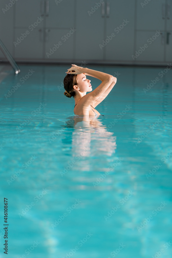 woman with closed eyes swimming in pool of luxury spa center