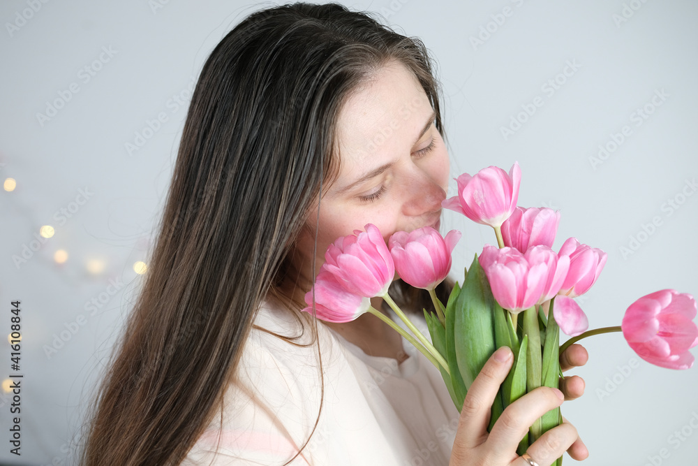 young woman, girl with long blond hair bouquet of pink tulips holds a bouquet of pink tulips in her hands, concept spring, mother's day, valentine's, birthday, holiday
