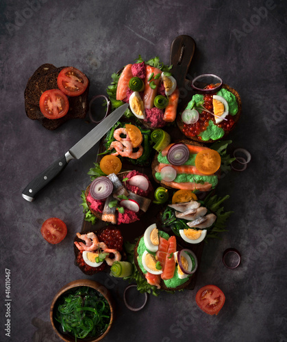 Smorrebrod, traditional Danish open sandwiches, dark rye bread with various fillings, black background, top view