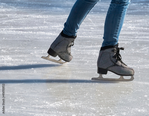 Close up with the legs of a woman with skates on ice. Ice skating recreational activity.
