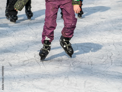 Close up with a young adult with skates on ice. Ice skating recreational activity.