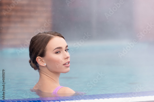 young woman looking away and taking bath in outdoor hot spring pool