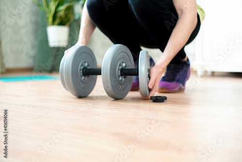 person doing workout and put on a weght disc on a barbell dumbbell