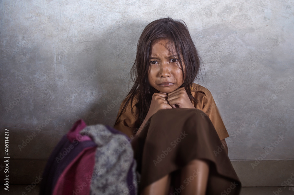 Fototapeta premium young scared and helpless 7 or 8 years old female child in school uniform suffering discrimination and harassment at school sitting on floor crying in bullying problem concept