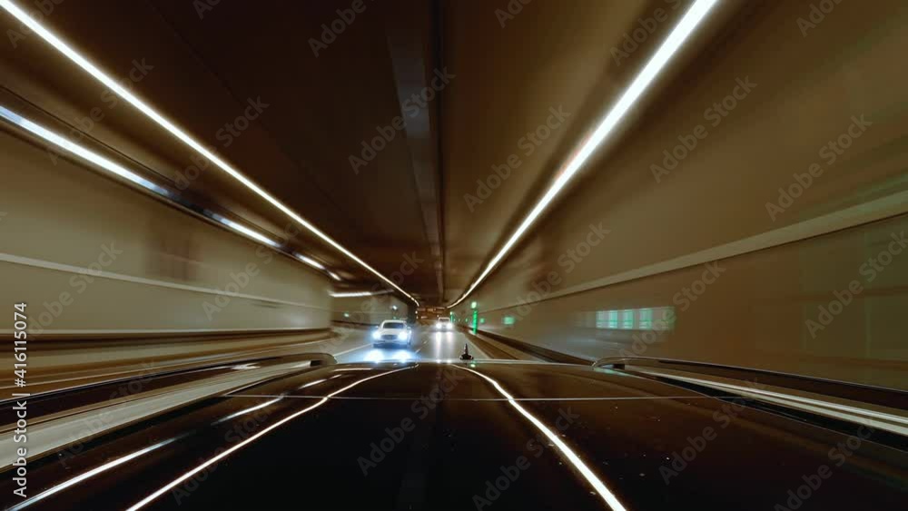 Driving fast through a urban tunnel with lights and green illuminated exit doors with the view at behind by a camera mounted at the cars roof Driving fast through a urban tunnel with lights and green illuminated exit doors with the view at behind by a camera mounted at the cars roof
