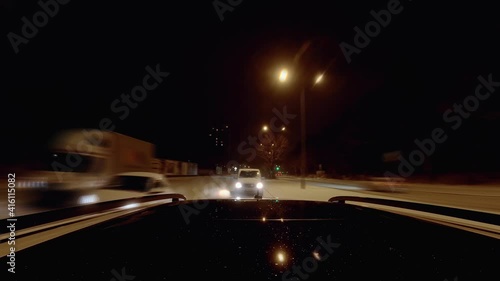 Accelerate a car at a snowy winter street, looking behind from the car top at the following fast cars in an urban aera at night photo