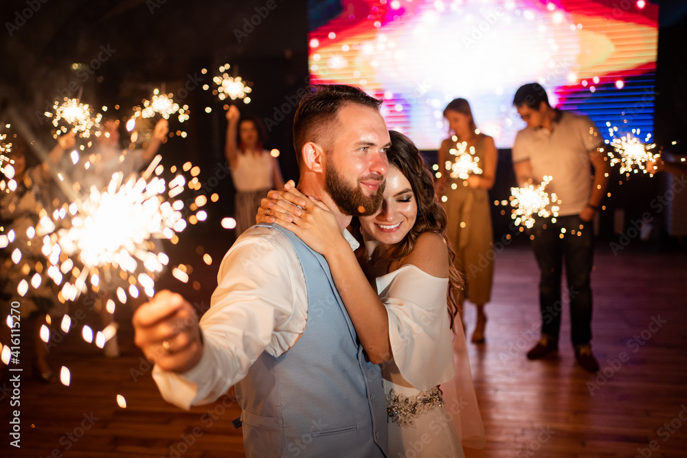 newlyweds with sparklers in night say goodbye to guests in the restaurant