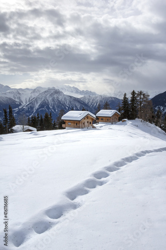 Footprints on snow with Swiss Alps winter landscape and chalets at the background