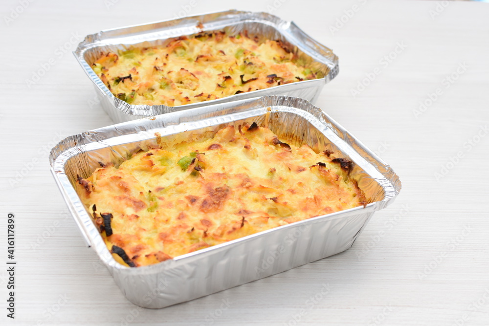 Baked chicken and mushroom cannelloni, bathed in cream in cheese sauce gratin on white wooden background