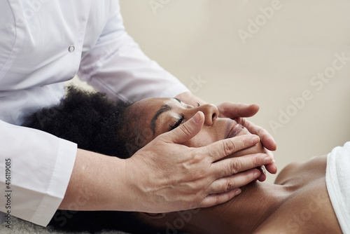 Young woman having anti-stress facial massage in salon at spa resort. Face massage. Facial skin care. Woman at beauty spa salon
