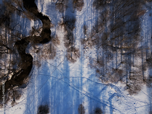 Flight over the winter park. The drone loops over the river, camera down. Aerial photography of the winter landscape.