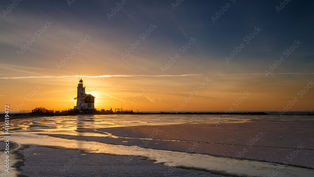 Winter landscape at the Lighthouse Paard van Marken Netherlands. On a cold day, temperature -7 degree during sunset. The IJsselmeer is frozen and by strong wind the shore was covered with ice Winter landscape at the Lighthouse Paard van Marken Netherlands. On a cold day, temperature -7 degree during sunset. The IJsselmeer is frozen and by strong wind the shore was covered with ice