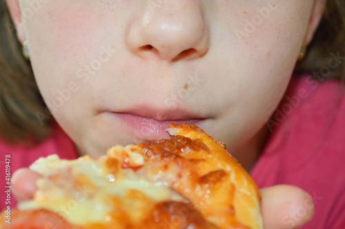 close-up - a girl eats pizza  holding a slice of pizza in her hand