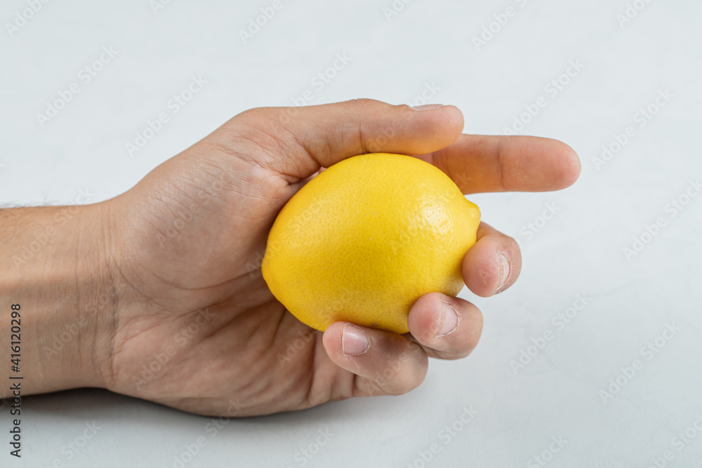 Hand holding a whole fresh lemon with on a white background Hand holding a whole fresh lemon with on a white background