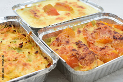 Baked chicken and mushroom cannelloni, bathed in cream in cheese sauce gratin on white wooden background