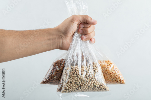 Man hand holding bags with raw beans on a white background photo