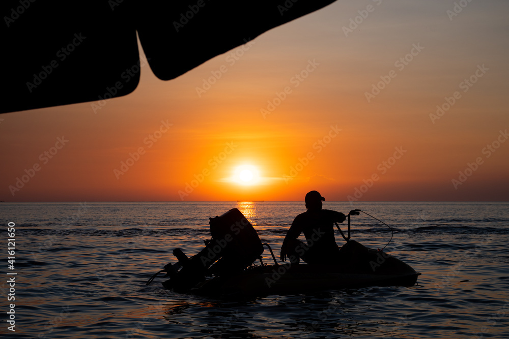 silhouette of man sitting on his jetski against sunset