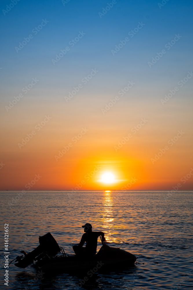 silhouette of man sitting on his jetski against sunset