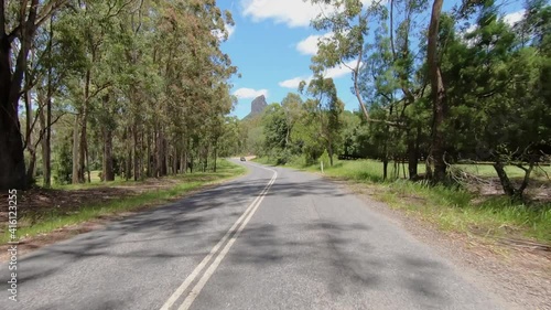 Rear facing driving point of view POV of a deserted Queensland country road with Glasshouse Mt Coonowrin - ideal for interior car scene green screen replacement photo