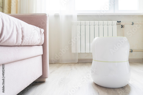 air humidifier in the room near the radiator heating, humidification of dry air and water purification of indoor air, selective focusing, tinted image, sun glare