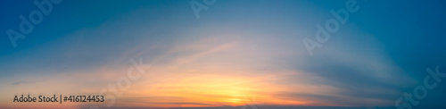Sunset wide panorama of the sunset in clear skies for the site header. Wide Panorama of Blue sky with Bright yellow sun Glare in the Evening. © Andrii Chagovets