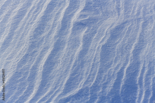 Snowy surface. Wavy contours. Crystals shine in the sun.